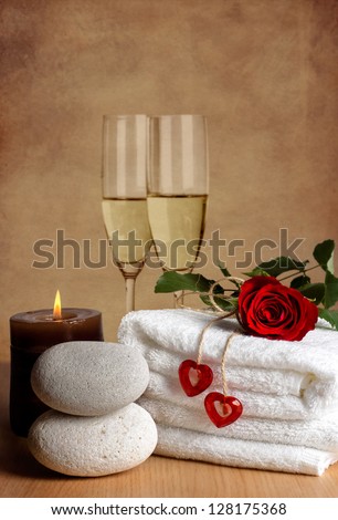 Romantic spa decoration with candles, spa stones, rose and champagne on a vintage background