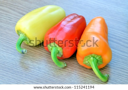 fresh yellow, red and orange bell peppers isolated on wood
