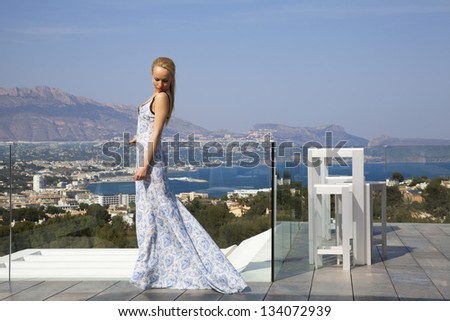 The beautiful blonde girl in a fashion blue dress on the sea