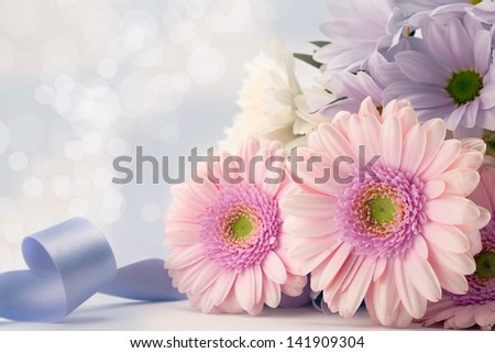 Gerbera daisies with blue ribbon and diffused background.