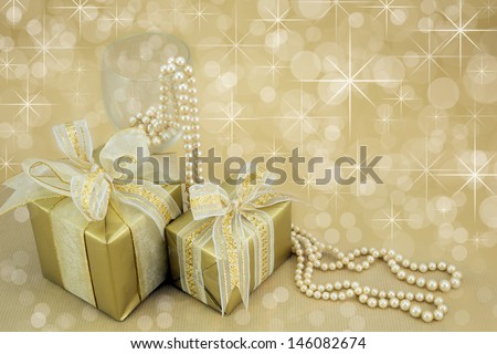Two gold wrapped presents with ribbon,pearls and wine glass