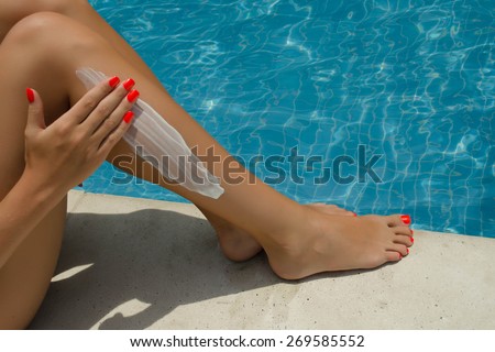 Woman apply cream on her smooth tanned legs