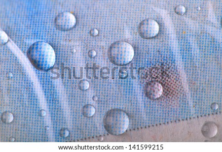 Close up of water drops on a rolled up newspaper wrapped in plastic.
