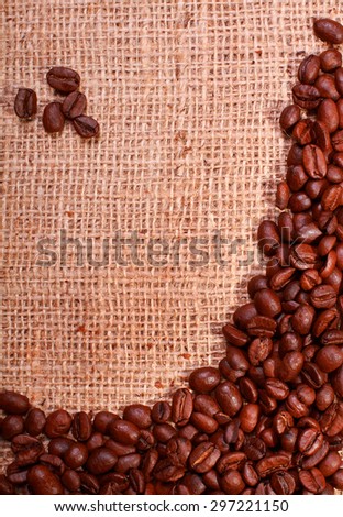 Roasted coffee beans border on a burlap background