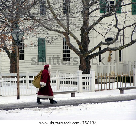 santa claus carrying bag walking on the sidewalk in winter scenery