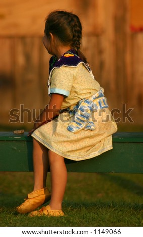 Little indian girl sits on bench waiting to perform Little American Indian girl performs at a local fair