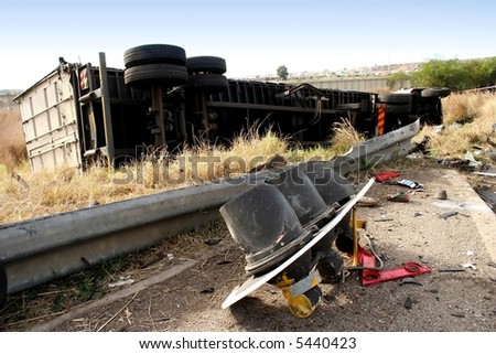 An overturned truck and smashed barrier and traffic control lights