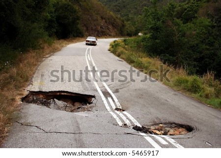 A badly damaged road with sink holes due to heavy rain falls