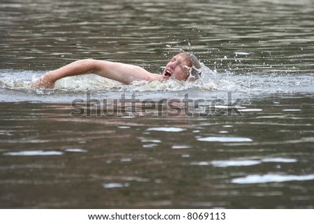 Young lad swimming in a river taking a breath with his mouth wide open and water splashing