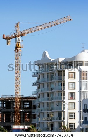 A tall crane at a building site next to a modern apartment block