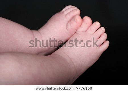A tiny baby\'s feet and toes against a black background