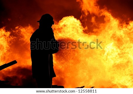 Fireman fighting a raging fire with huge flames of burning timber