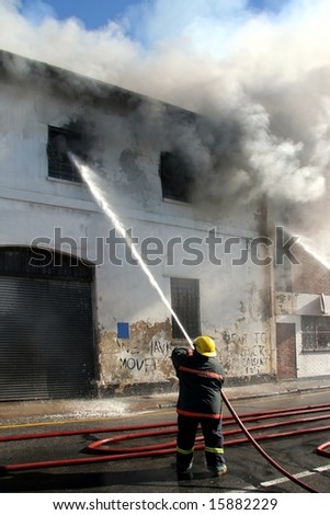 Fireman fighting a fire in a burning building with a water hose