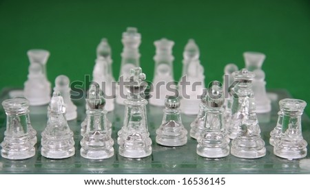 Crystal or glass chess men on a ches board and green background