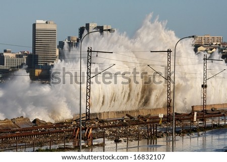 Storms waves exploding against a wall and flooded railway line