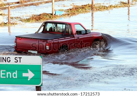 Red truck driving through deep water on a flooded road
