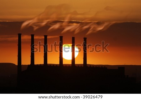 Smoking factory chimneys at sunset adding to global warming