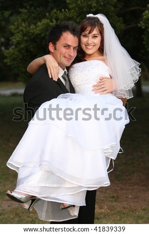 stock photo Beautiful wedding couple with the bride been carried by the