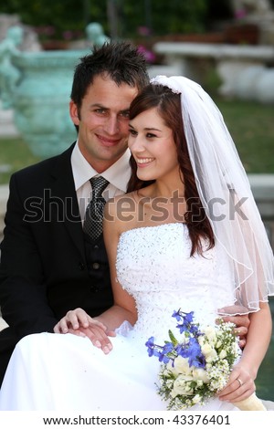 Beautiful smiling young wedding couple sitting together at their garden reception