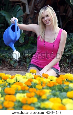 Pretty young lady with lovely smile watering flowers with a watering can