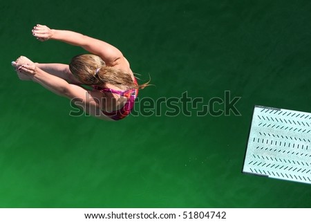 Diver above green water with end of diving board visible