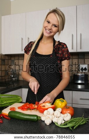 Lovely smiling blond housewife preparing vegetables in the kitchen