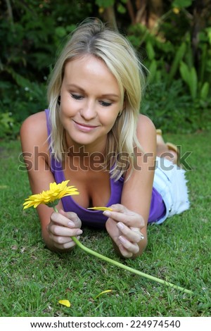 Pretty young lady playing he loves me he loves me not with yellow daisy flower