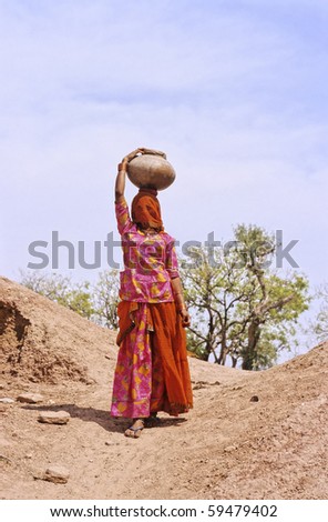 Indian veiled woman carrying water