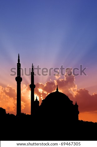 Istanbul Turkish mosque outlined by sunset showing dome and minarets.