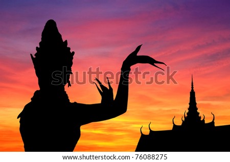 Woman performing typical Thai dance. Movement outlined  by sunset back-light. Khmer temple as background