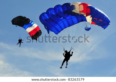 Two colorful parachutes on blue sky.