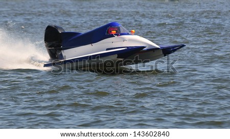 Outboard of competition at full speed on blue water of a river.