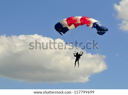 Blue white and red sail parachute on blue sky with white cloud.