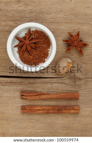 Chinese five spice in a ramekin with star anise nutmeg and cinnamaon on old weathered wood