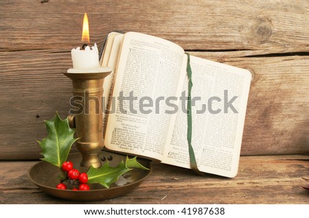 Antique prayer book open on a Christmas prayer lit by candle light