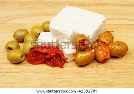 Olives, feta cheese and sun blushed tomatoes on a wooden board