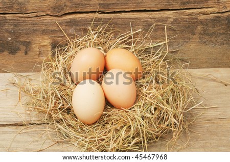 Hens eggs in a nest of hay on rustic wood
