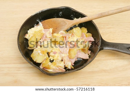 Fried potato, ham and eggs in a pan