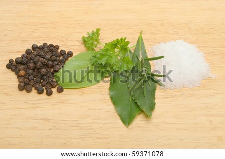 Herbs, salt and pepper on a wooden board