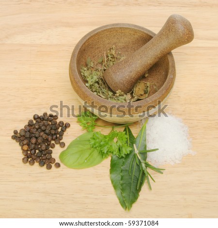 Herbs, salt and pepper with a pestle and mortar on a wooden board