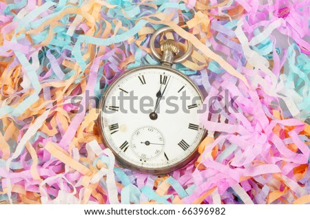 New year theme, antique pocket watch at midnight surrounded by paper party streamers