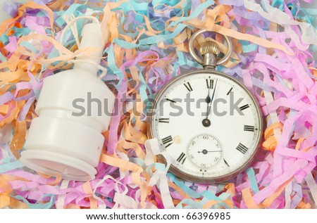 New years theme an antique pocket watch at midnight and a party popper and streamers
