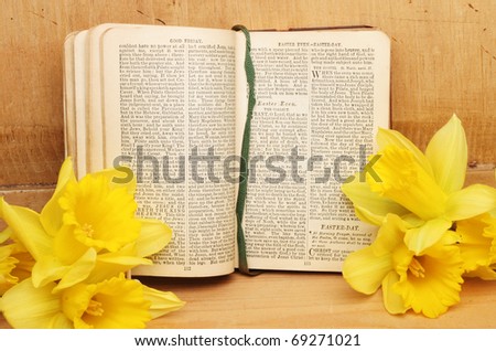 Antique prayer book open on Easter prayers surrounded by daffodil flowers against an old wooden panel