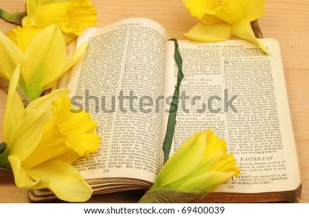 Antique prayer book open on Easter prayers surrounded by yellow daffodil flowers