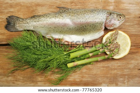 Fresh rainbow trout with dill, asparagus and lemon on old weathered wood