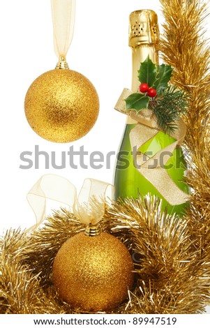Christmas theme,bottle of champagne decorated with holly, pine needles and a gold ribbon bow surrounded by tinsel and gold glitter bauble with copy space to the left
