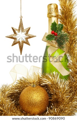 Christmas theme,bottle of champagne decorated with holly, pine needles and a gold ribbon bow surrounded by tinsel and gold glitter bauble and gold star