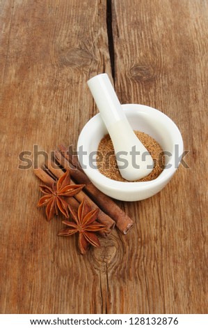 Pestle and mortar with Chinese five spice, star anise and cinnamon on a background of old weathered wood