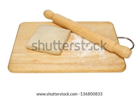 Block of ready made pastry with flour and a rolling pin on a wooden board isolated against white