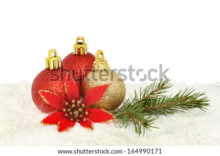 Red and gold Christmas baubles with a red silk flower and pine needles on a bed of snow